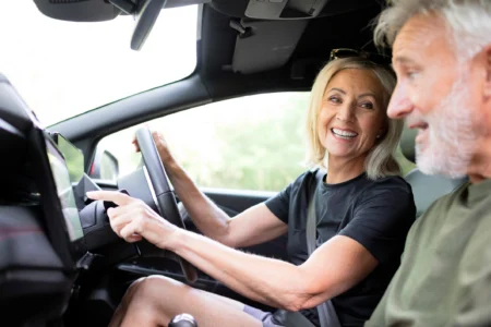 UK drivers preparing for a trip in the EU, older couple in car using sat nav and wearing seatbelts with compliant number plates.