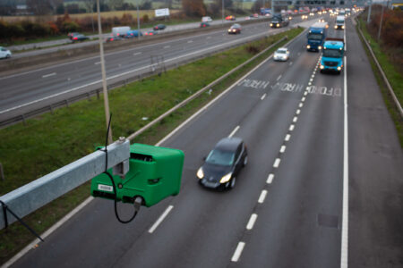 Vehicles on motorway in sight of ANPR camera surveillance, highlighting legal compliance for ghost number plates.